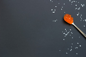 Fototapeta na wymiar Red caviar in spoon on black table