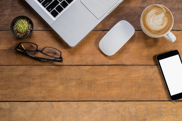 Office desk table with laptop, glasses, coffee cup, mouse, blank screen smartphone and cup of coffee.Top view with copy space.Office supplies and gadgets concept.