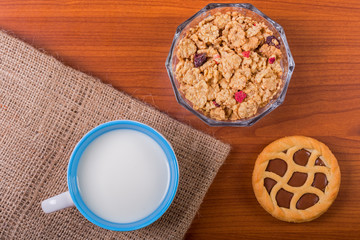 Cup of milk with chocolate tart and cereals - top view