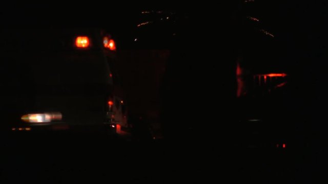 A parked fire truck and ambulance with lights flashing on the street during a fireworks display on the 4th of July. HD 1080p.