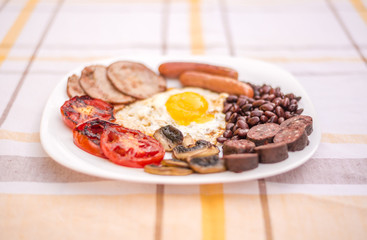 Full English fried breakfast with bacon, egg, sausages, black pudding, mushrooms, grilled tomatoes and baked beans.