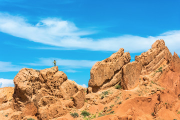 A man stands on a huge rock against the blue sky, Kyrgyzstan.