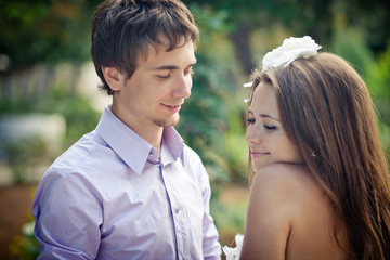 Handsome young groom looks at bride with love while she stands s