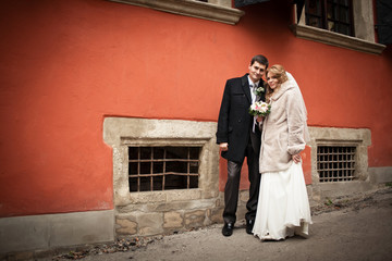 Cute adult wedding couple poses before old orange house