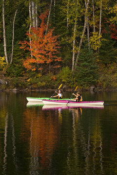 Two young women kayaking on Oxtongue Lake in autumn, Mukoka, Ontario, Canada.