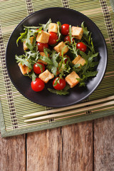 Asian salad with fried tofu, tomatoes and arugula close-up. vertical top view
