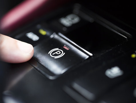 finger pressing the  Electronic Parking Brake button