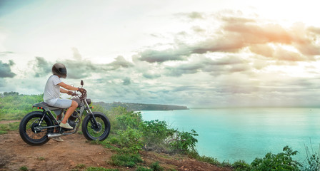 Obraz na płótnie Canvas Motorcycler on the top of the mountain over the ocean