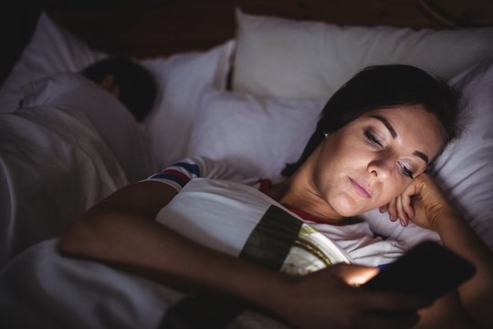 Woman using mobile phone while lying on bed