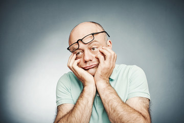 Tired middle-aged man suffering fatigue and rubbing his cheek
