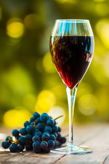 Glass with red wine on the wooden table. Shallow depth of field. Toned image.