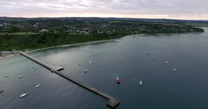Slow cinematic desend from high altitude towards the Flinders pier. Flinders, Mornington Peninsula, Victoria, Australia.