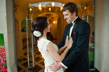 Bride lies her hands on groom's chest while they stand in restau