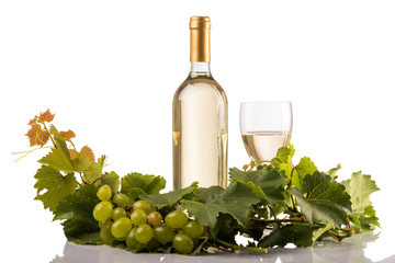 White wine glass and bottle with vine leaves and grapes isolated on white background