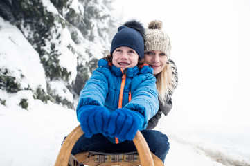 Mother with son on sledge. Foggy white winter nature.