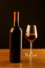 Fototapeta na wymiar Red wine bottle with glass on black background