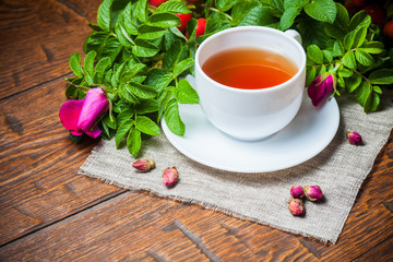 Healthy tea with a dogrose on wooden table