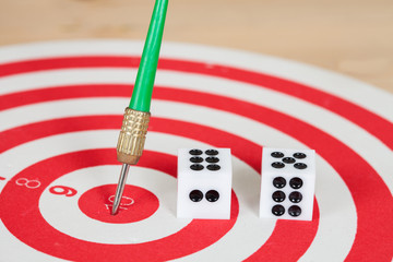 Dice on dart board with green dart arrow
