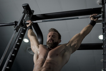 Entrenando en el gimnasio. Hombre con grandes músculos levantando peso mientras entrena en el...