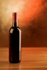 Fototapeta na wymiar A red wine bottle on wooden table and golden background