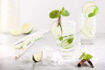 Cold detox cocktail with cucumbers, lime, mint and cinnamon with ice in the glass on the table