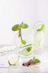 Cold detox cocktail with cucumbers, lime, mint and cinnamon with ice in the glass on the table