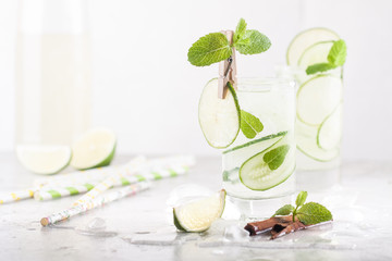 Cold detox cocktail with cucumbers, lime, mint and cinnamon with ice in the glass on the table