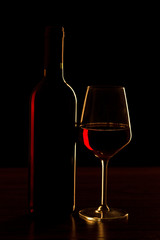 Red wine bottle with glass on black background - silhouette