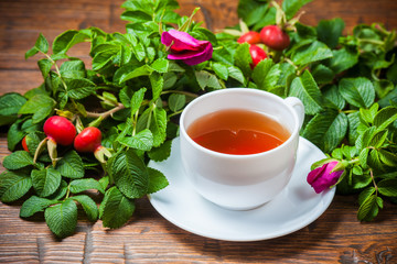 Healthy tea with a dogrose on wooden table
