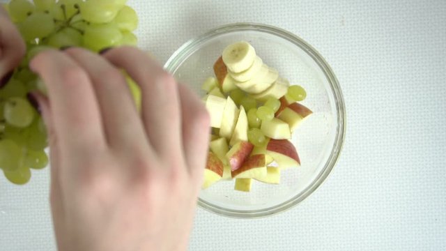 Putting grapes into fruit salad