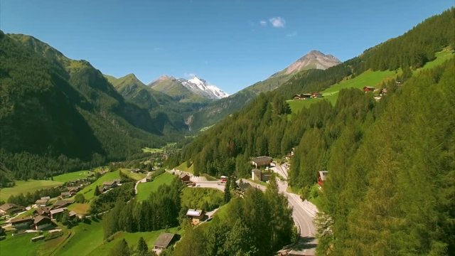 Aerial view of scenic village Heiligenblut in picturesque green valley in the Alps with the highest peak of Austria, Groossglockner, visible in the background