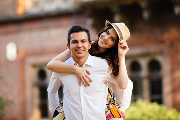 Man giving his pretty girlfriend a piggy back on a sunny day in the city