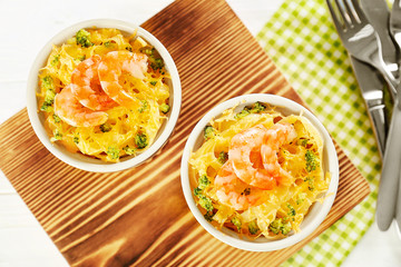 Portions of delicious pasta with shrimps on wooden board