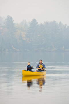 Young/middle-aged man fishing with son from canoe on Source Lake, Algonquin Provincial Park, Ontario, Canada.