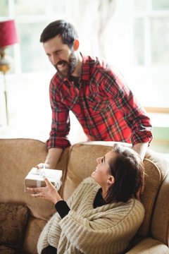 Man Surprising Woman With A Gift In Living Room