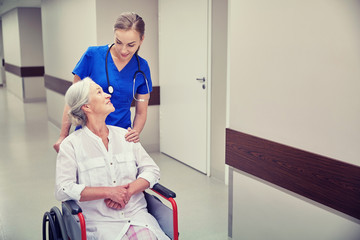 nurse with senior woman in wheelchair at hospital