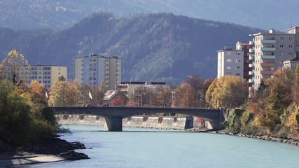 Colorful day at the Inn river with the sun shinning at the autumn colored trees and the green river water