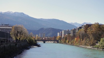 Colorful day at the Inn river with the sun shinning at the autumn colored trees and the green river water