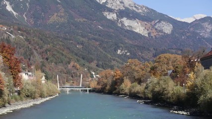 Colorful day at the Inn river with the sun shinning at the autumn colored trees and the green river water
