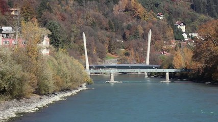 Colorful day at the Inn river with the sun shinning at the autumn colored trees and the green river water