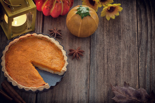 Thanksgiving pumpkin pie with pumpkin and lantern on wooden background 