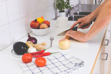 Close up on man hands cutting fresh vegetable on light interior kitchen
