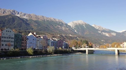 Colored houses by the Inn river with the mountains in the background at Mariahilfstrasse in Innsbruck, Austria