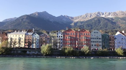 Colored houses by the Inn river with the mountains in the background at Mariahilfstrasse in Innsbruck, Austria
