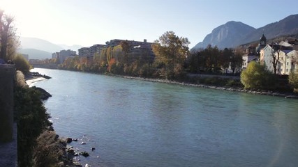Colorful day at the Inn river with the sun shinning at the autumn colored trees and the green river water