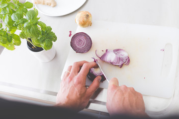 top view on hands of housekeeper chopping fresh vegetables for lunch in light interior kitchen background