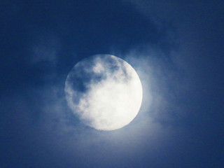 Blue sky with Full Moon and clouds rolling over it 