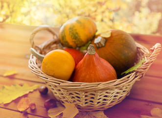 close up of pumpkins in basket on wooden table