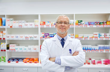 Naklejka na ściany i meble senior male pharmacist in white coat at drugstore
