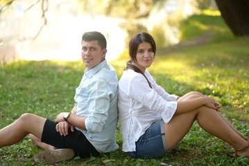 Couple siting back in back in nature